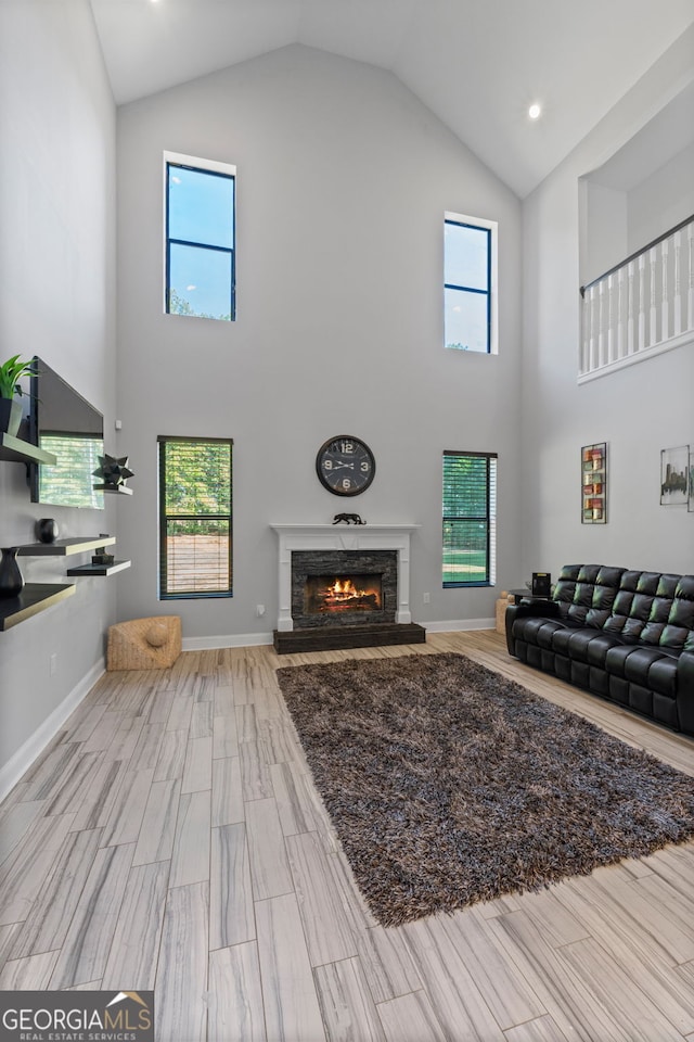 living room featuring high vaulted ceiling, a fireplace, and a healthy amount of sunlight