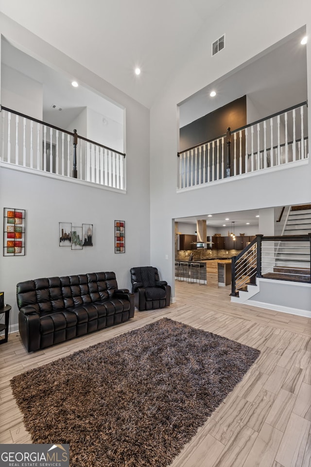 living area with high vaulted ceiling, visible vents, recessed lighting, stairway, and wood finished floors