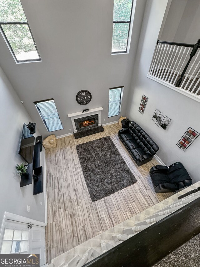 living room featuring a glass covered fireplace, a towering ceiling, a skylight, and wood finished floors