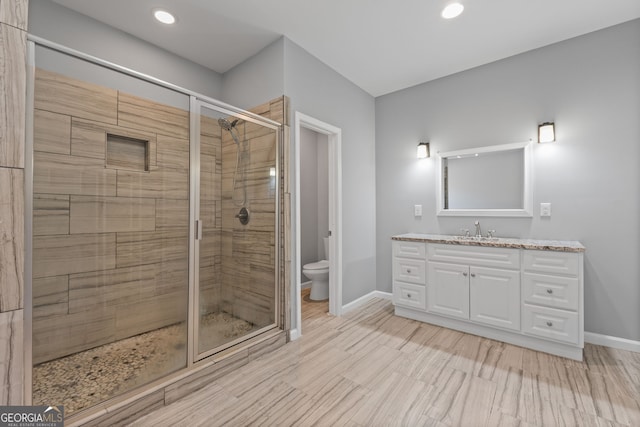 full bathroom featuring toilet, a stall shower, baseboards, and vanity