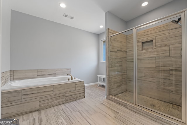 bathroom with independent shower and bath and hardwood / wood-style floors