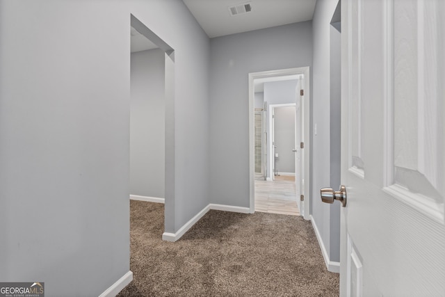 hallway with visible vents, baseboards, and carpet floors