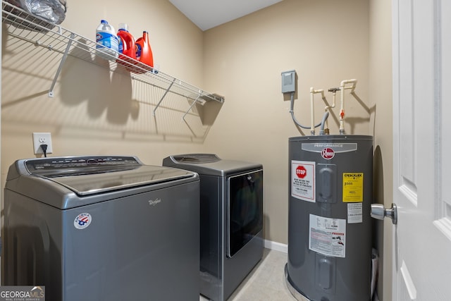 clothes washing area featuring electric water heater, baseboards, washing machine and dryer, and laundry area