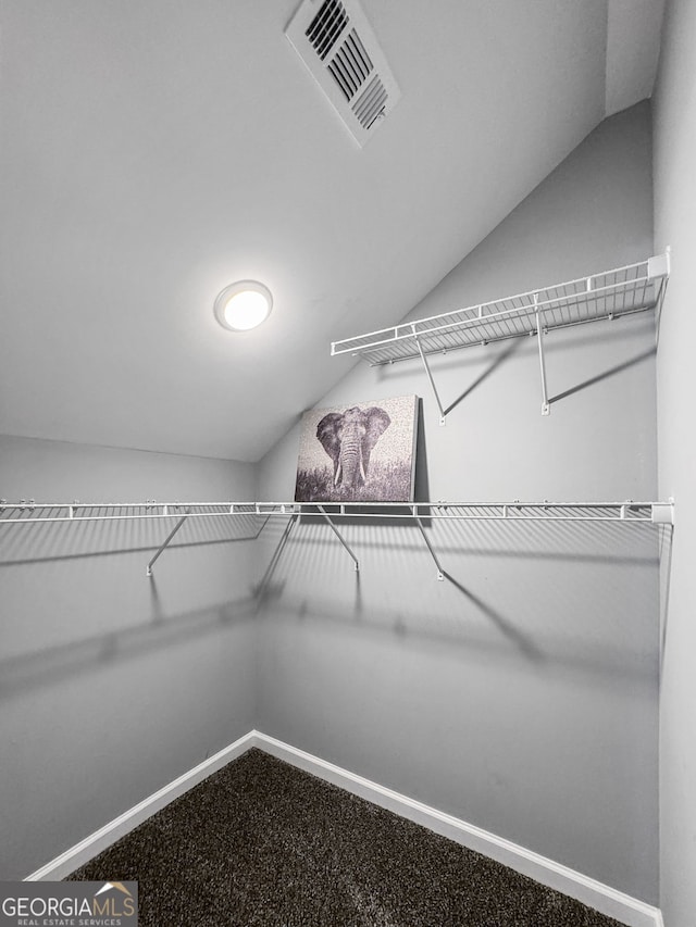 spacious closet featuring visible vents, vaulted ceiling, and carpet floors