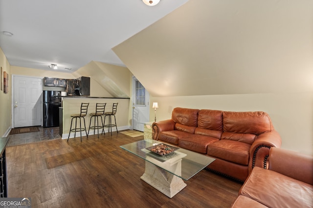 living area featuring dark wood-style flooring, baseboards, bar area, and vaulted ceiling