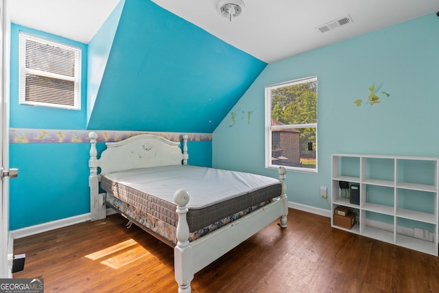 bedroom with visible vents, baseboards, vaulted ceiling, and wood finished floors