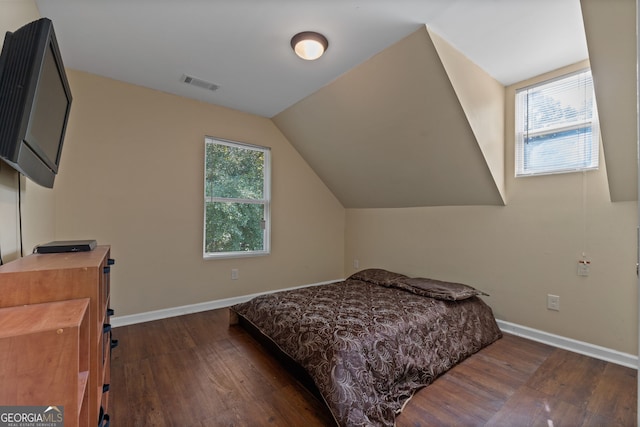 bedroom with vaulted ceiling, multiple windows, and dark hardwood / wood-style floors