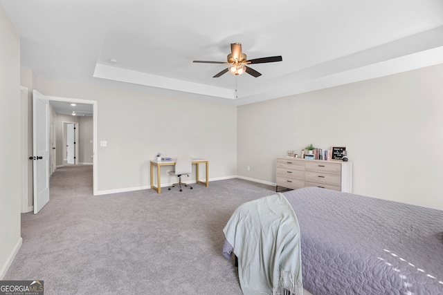 bedroom with ceiling fan, a tray ceiling, and carpet flooring