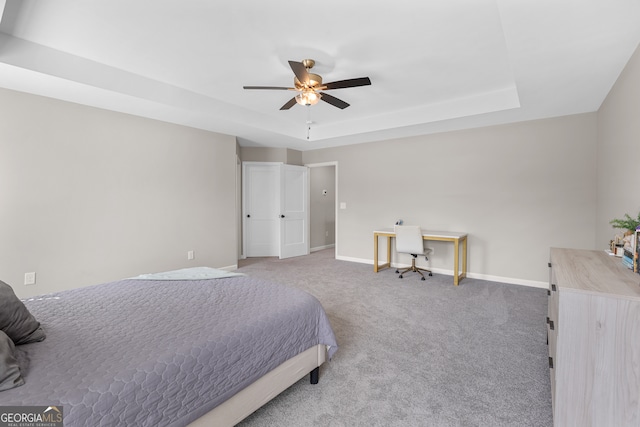 bedroom with a raised ceiling, carpet flooring, and ceiling fan