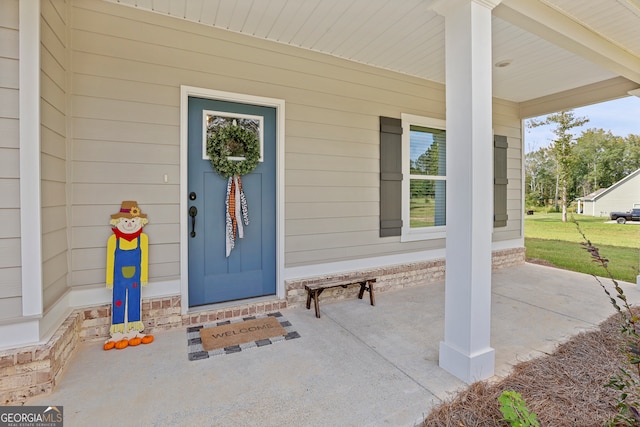 view of exterior entry featuring a yard and a porch