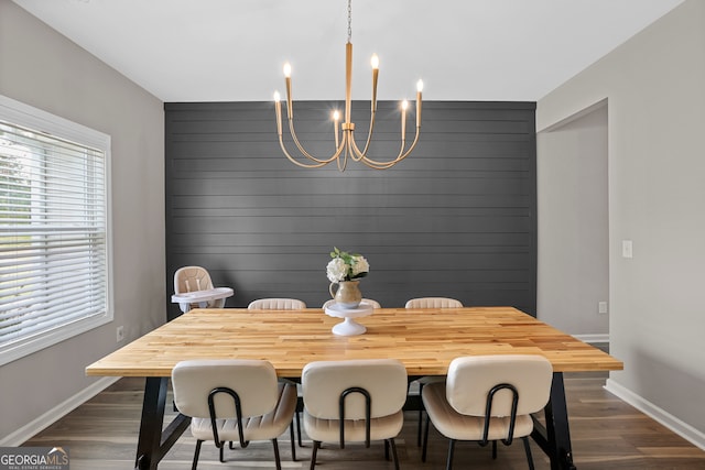 dining area featuring an inviting chandelier, wood walls, and dark hardwood / wood-style floors