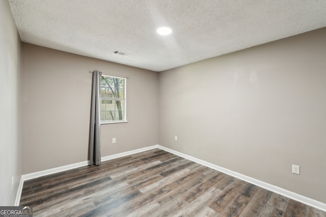 unfurnished room featuring a textured ceiling and dark hardwood / wood-style flooring