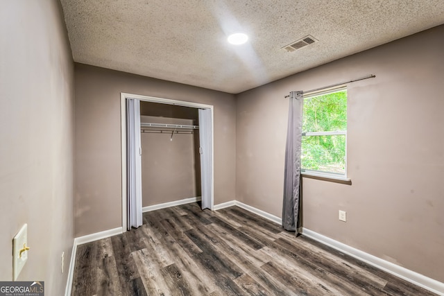 unfurnished bedroom featuring a closet, dark hardwood / wood-style floors, and a textured ceiling