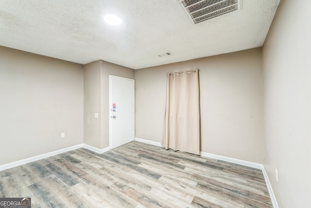 empty room featuring light wood-type flooring and a textured ceiling