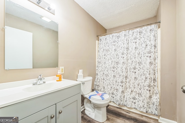 bathroom featuring a textured ceiling, hardwood / wood-style flooring, a shower with shower curtain, vanity, and toilet