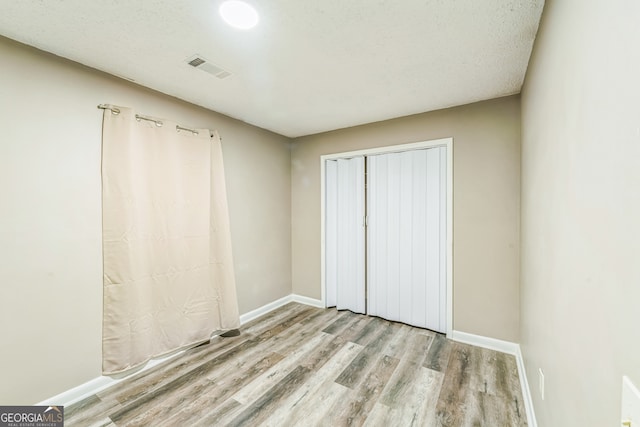 unfurnished bedroom with a closet, light hardwood / wood-style floors, and a textured ceiling