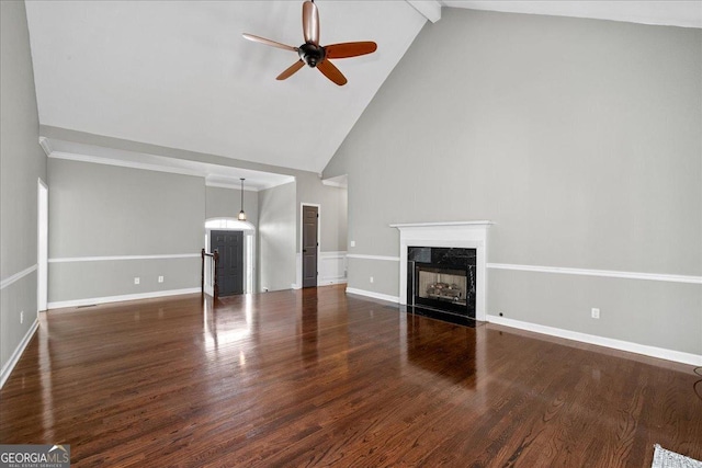 unfurnished living room featuring ceiling fan, a premium fireplace, wood finished floors, baseboards, and beam ceiling