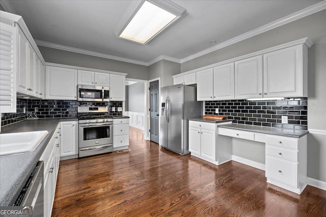 kitchen featuring appliances with stainless steel finishes, white cabinetry, built in desk, and dark wood-style floors