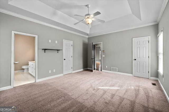 unfurnished bedroom featuring visible vents, a raised ceiling, and light colored carpet