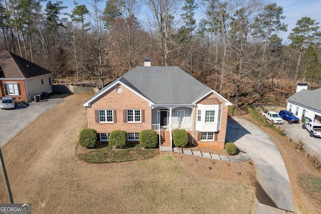 view of front facade with aphalt driveway, a front yard, brick siding, and a chimney