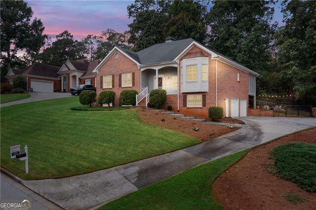 view of front of home with brick siding, a chimney, a garage, driveway, and a front lawn