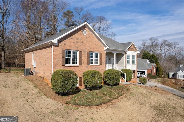 view of front of house with a chimney, central AC, and brick siding