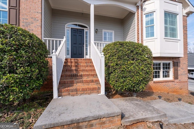 property entrance featuring brick siding and a porch