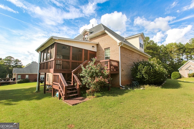 back of property with a sunroom, a yard, and a wooden deck