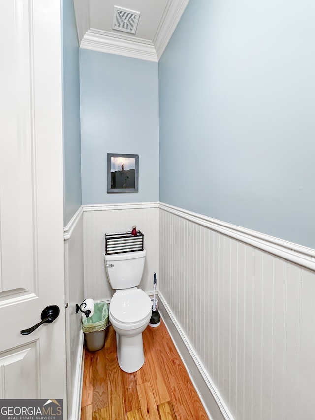 bathroom with hardwood / wood-style floors, crown molding, and toilet