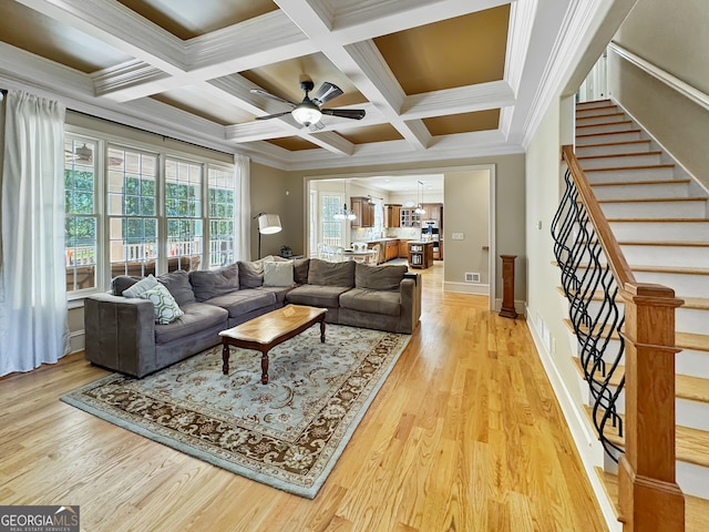 living room featuring light wood-type flooring, coffered ceiling, ornamental molding, and ceiling fan