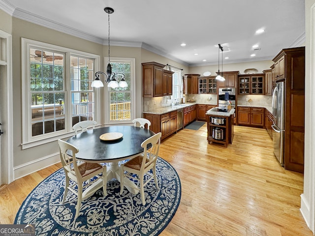 dining area featuring light wood-type flooring, ornamental molding, and sink