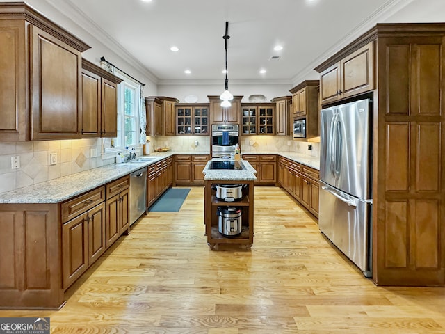 kitchen featuring stainless steel appliances, a center island, light wood-type flooring, and crown molding