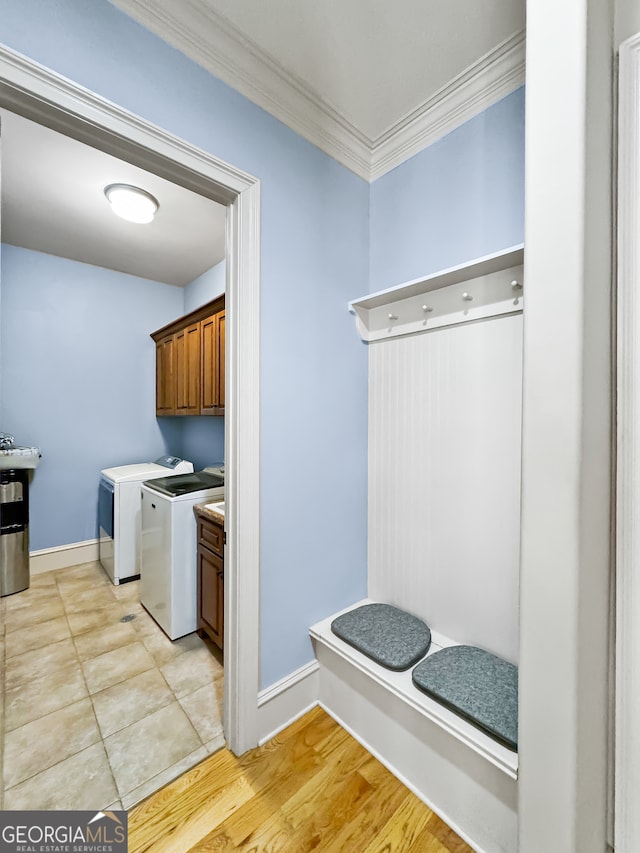 laundry area featuring light hardwood / wood-style flooring, cabinets, ornamental molding, and washing machine and clothes dryer