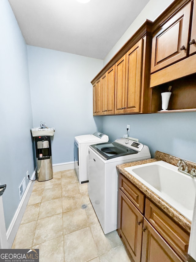 washroom with light tile patterned floors, cabinets, sink, and washing machine and dryer