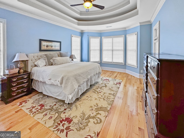 bedroom featuring crown molding, light hardwood / wood-style floors, ceiling fan, and a raised ceiling