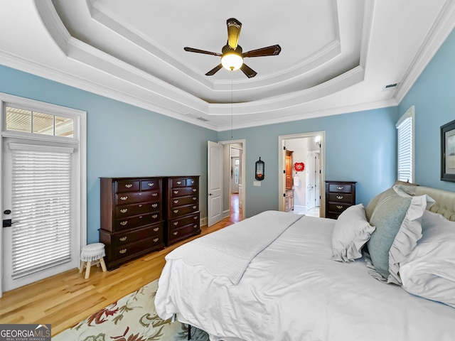 bedroom with a raised ceiling, ornamental molding, hardwood / wood-style floors, and ceiling fan