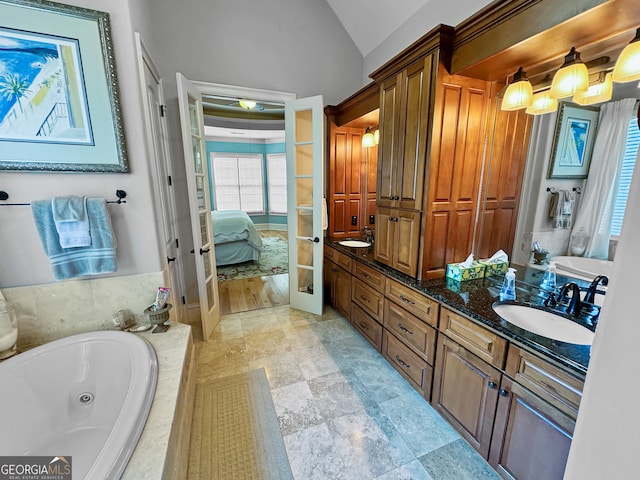 bathroom featuring french doors, a relaxing tiled tub, vanity, and lofted ceiling