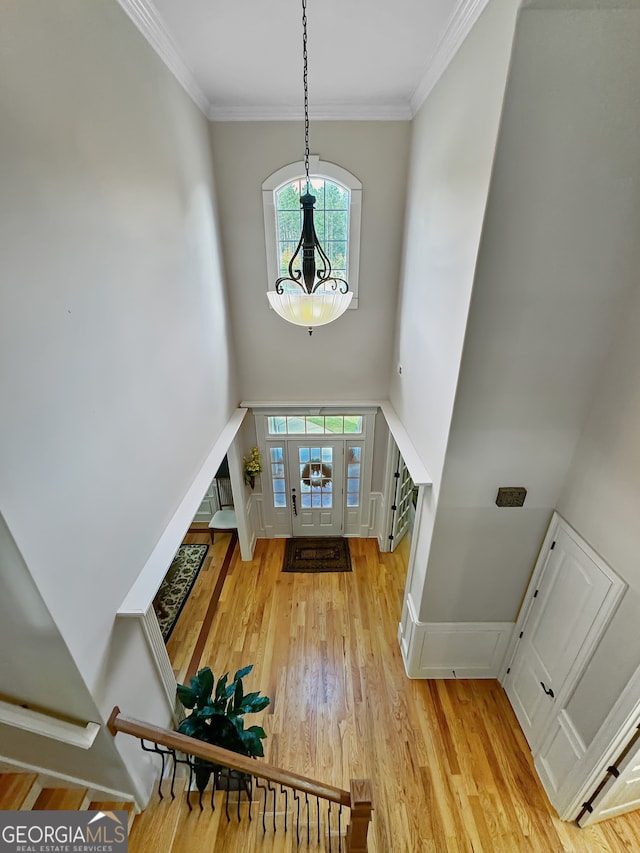 entrance foyer featuring a notable chandelier, light hardwood / wood-style floors, and ornamental molding