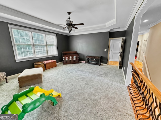 carpeted bedroom with crown molding, a tray ceiling, and ceiling fan