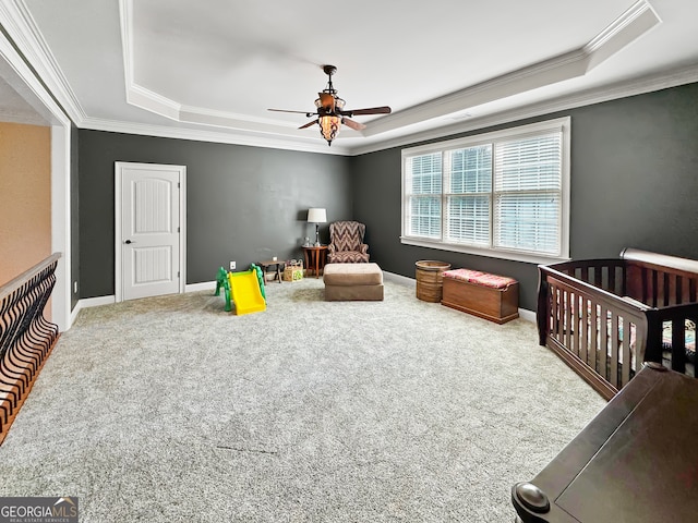 bedroom featuring carpet, a tray ceiling, ceiling fan, and a nursery area