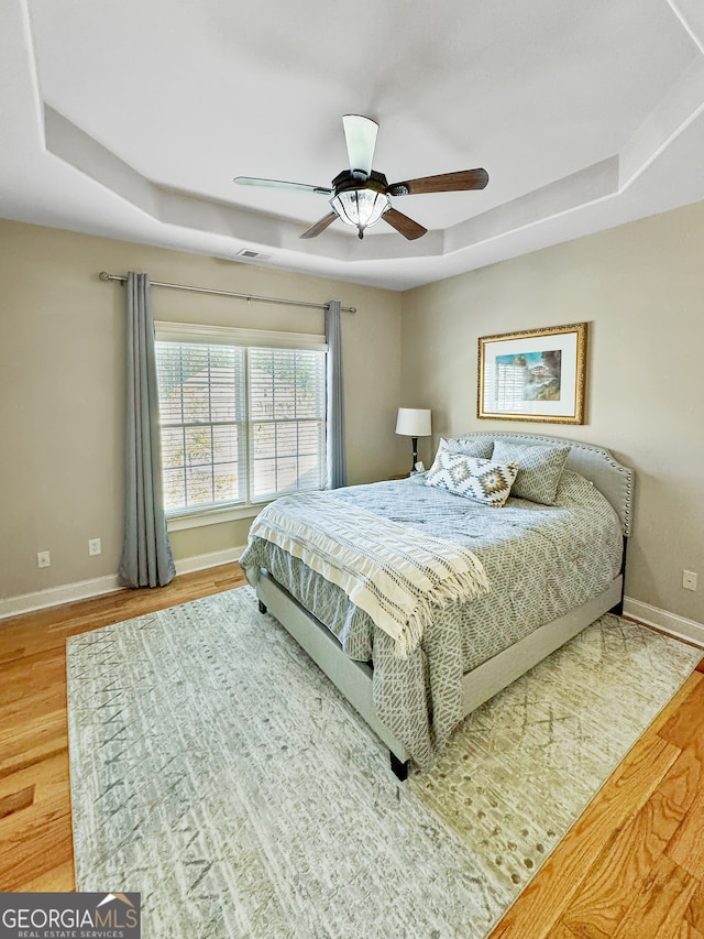 bedroom featuring a tray ceiling, ceiling fan, and hardwood / wood-style flooring