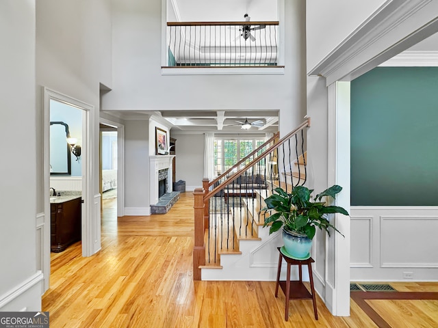 stairs with hardwood / wood-style flooring, ornamental molding, and a high ceiling