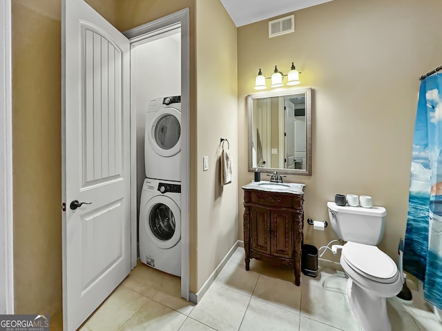 bathroom featuring curtained shower, vanity, stacked washer / drying machine, toilet, and tile patterned floors