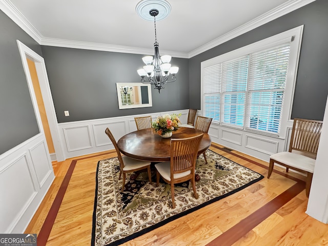 dining room with ornamental molding, a notable chandelier, and light hardwood / wood-style floors