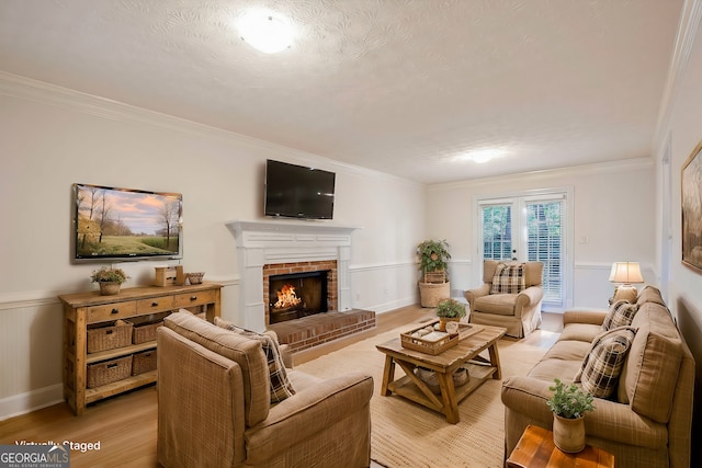 living room with a textured ceiling, light hardwood / wood-style flooring, ornamental molding, and a fireplace