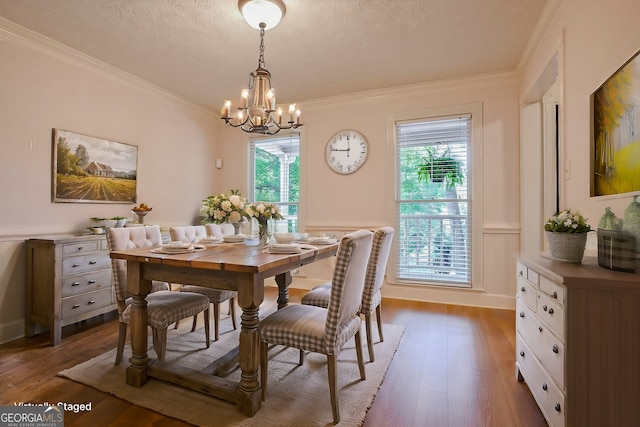 dining space featuring wood-type flooring, crown molding, a notable chandelier, and a textured ceiling