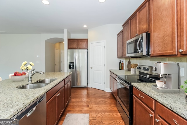 kitchen with light stone countertops, sink, appliances with stainless steel finishes, and hardwood / wood-style floors