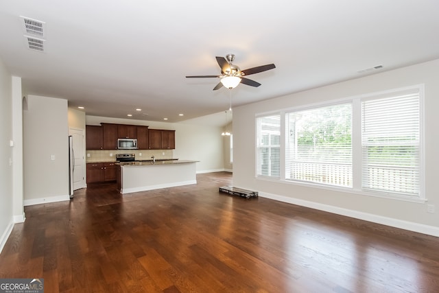 unfurnished living room with ceiling fan, sink, and dark wood-type flooring