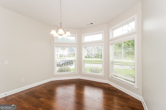 unfurnished dining area with wood-type flooring and a chandelier