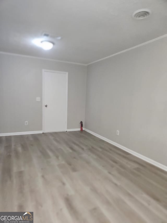 spare room with hardwood / wood-style flooring and crown molding